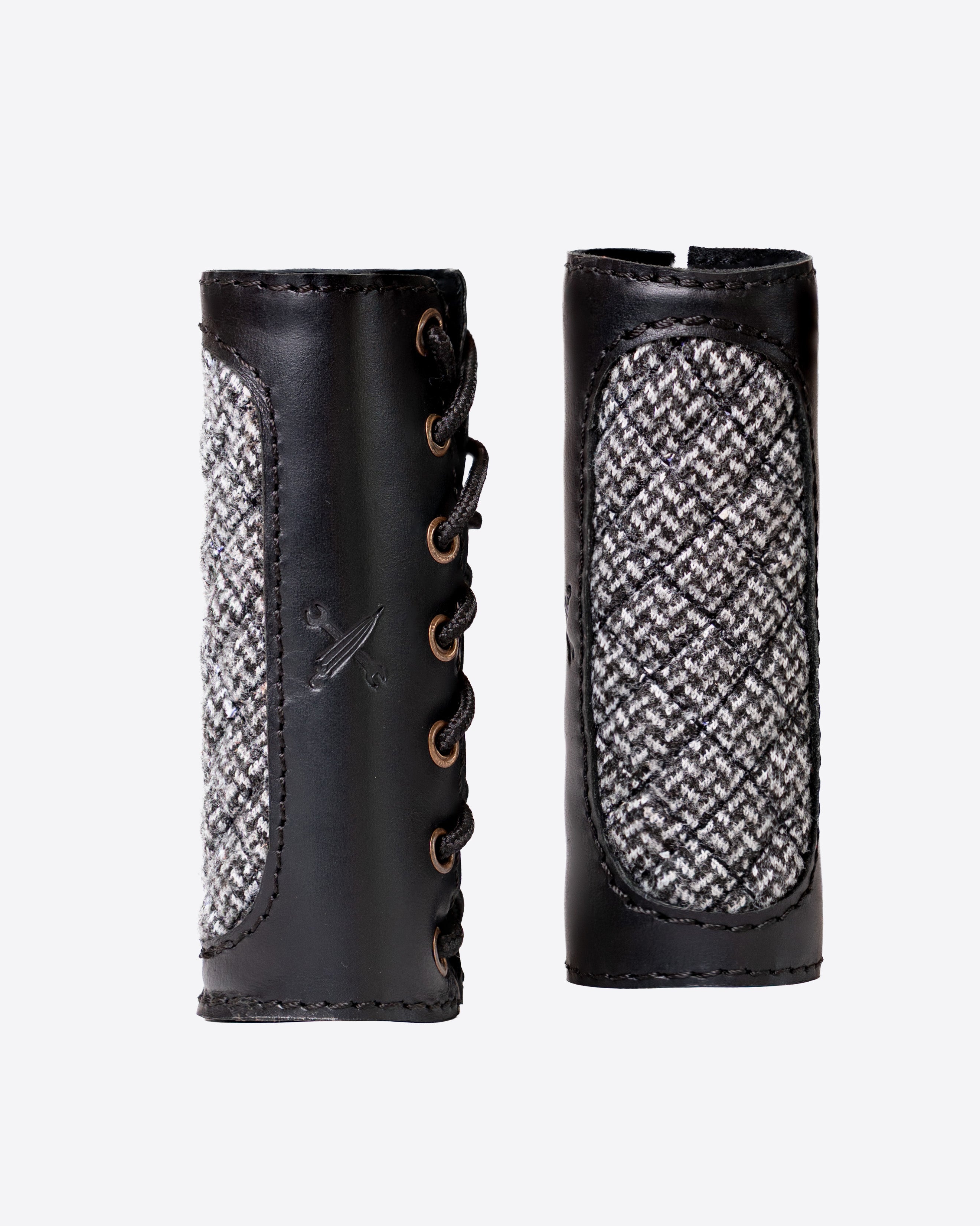 Pair of black leather grips with textured pattern on a white background