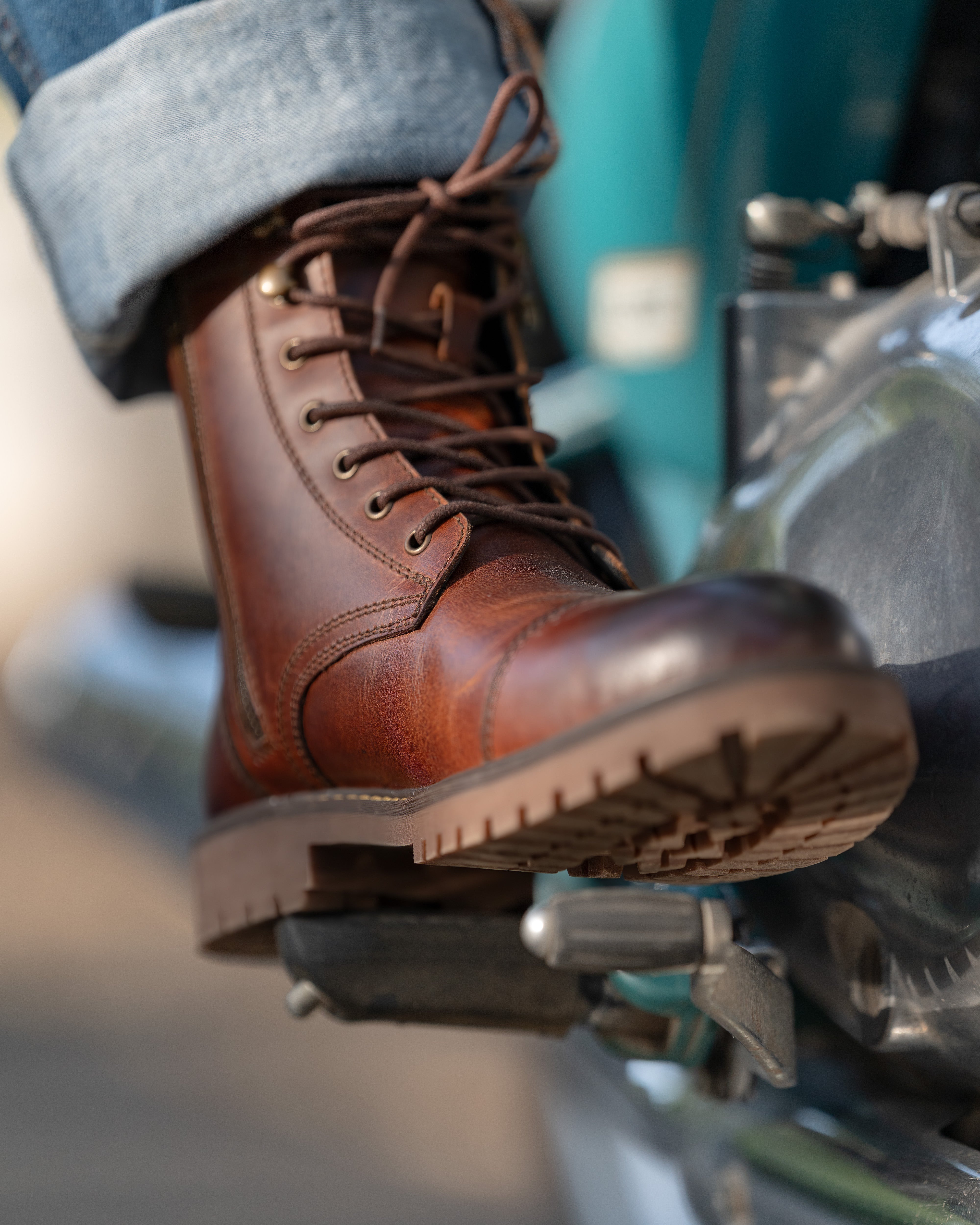 Brown leather boot on a motorcycle with blurred background