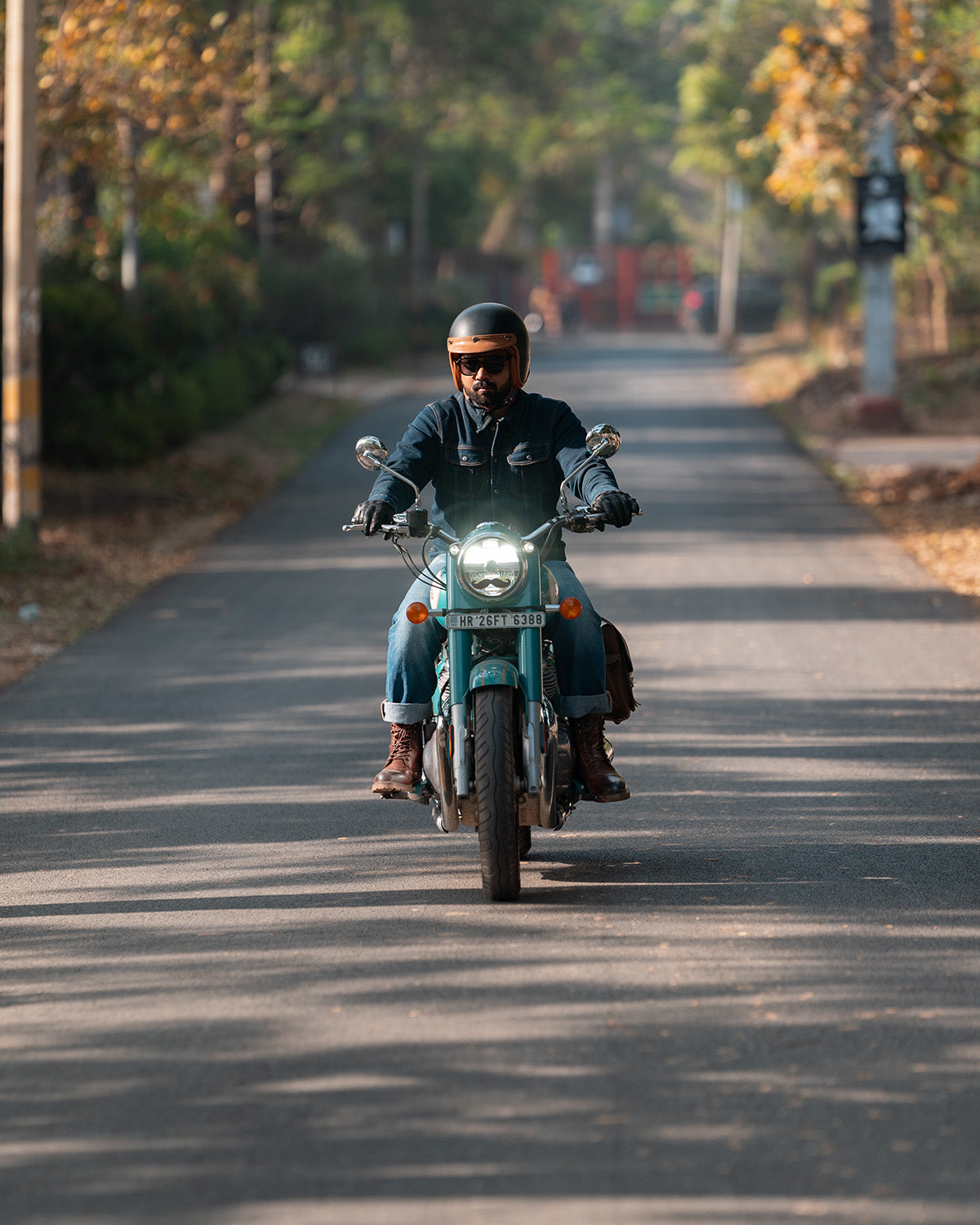 Person riding a motorcycle on a road with trees and a blurred background