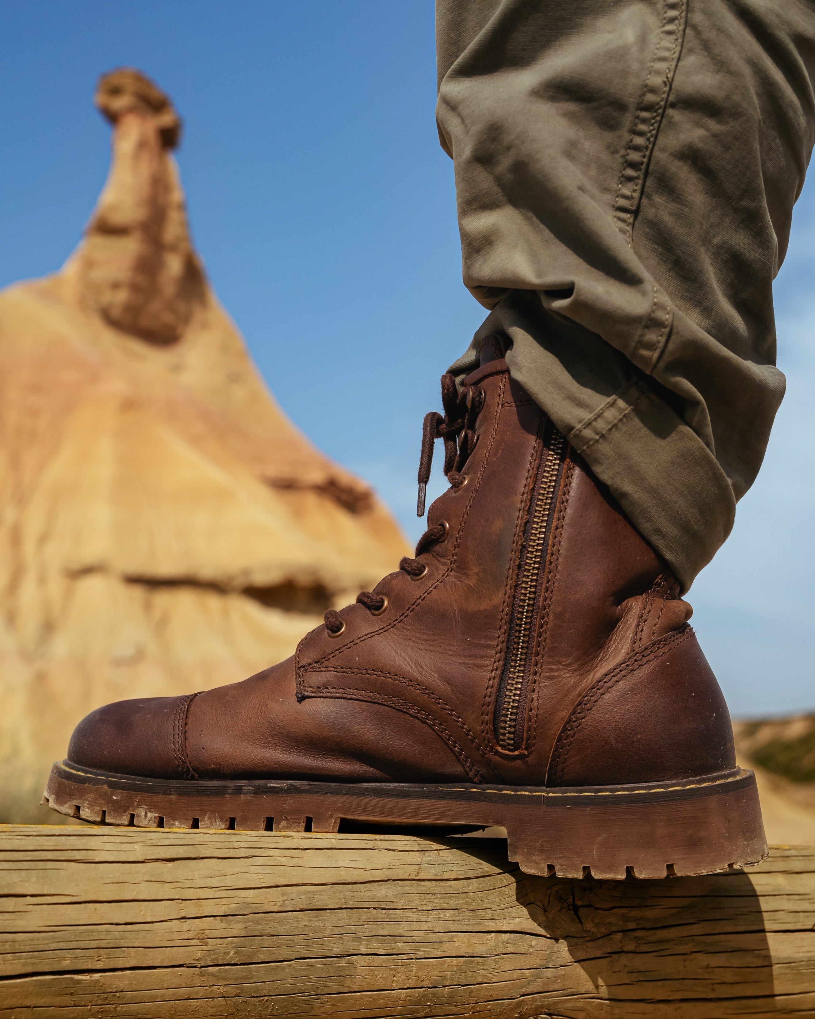 Brown leather boot with a desert landscape in the background