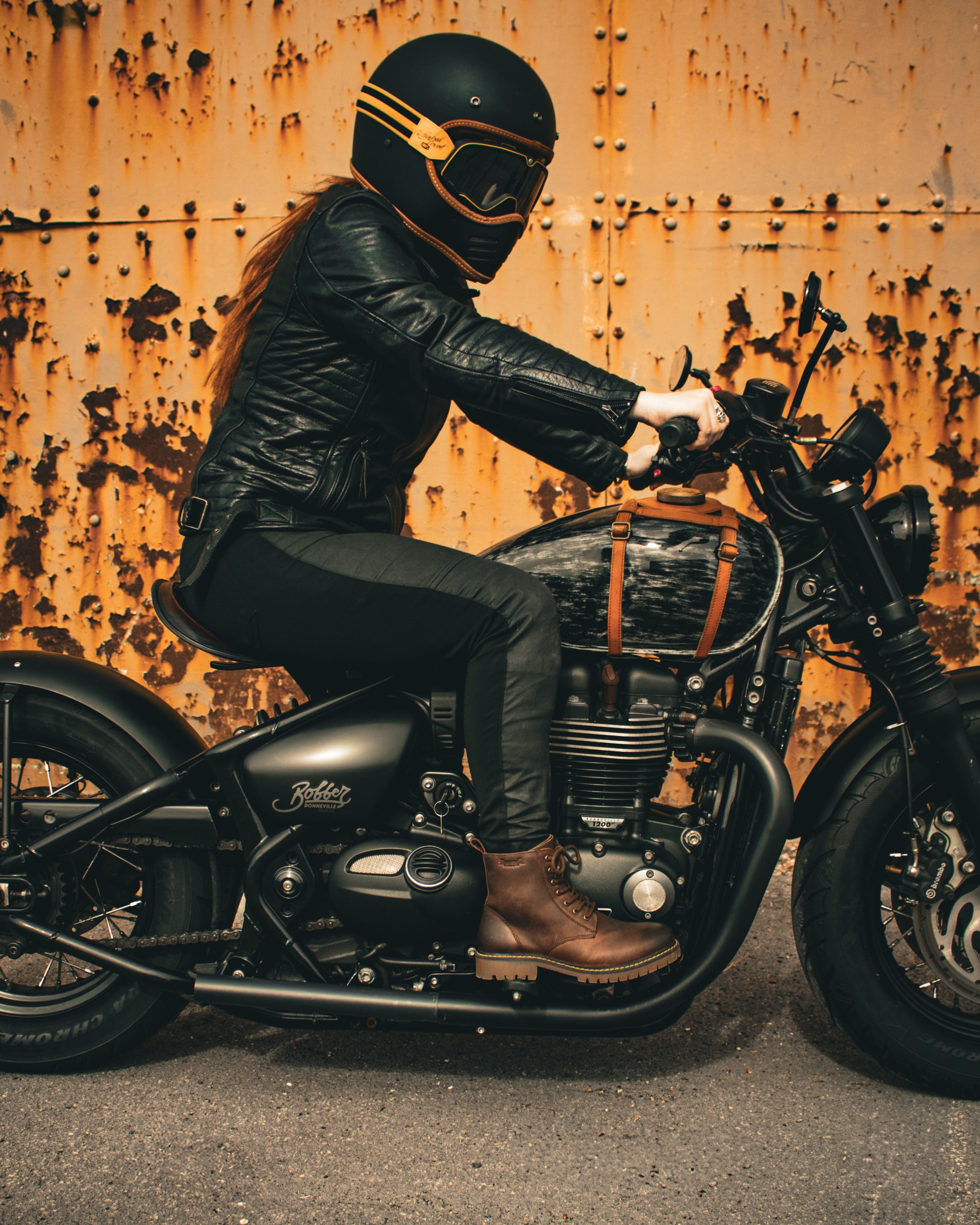 Person riding a motorcycle against a rusty wall background