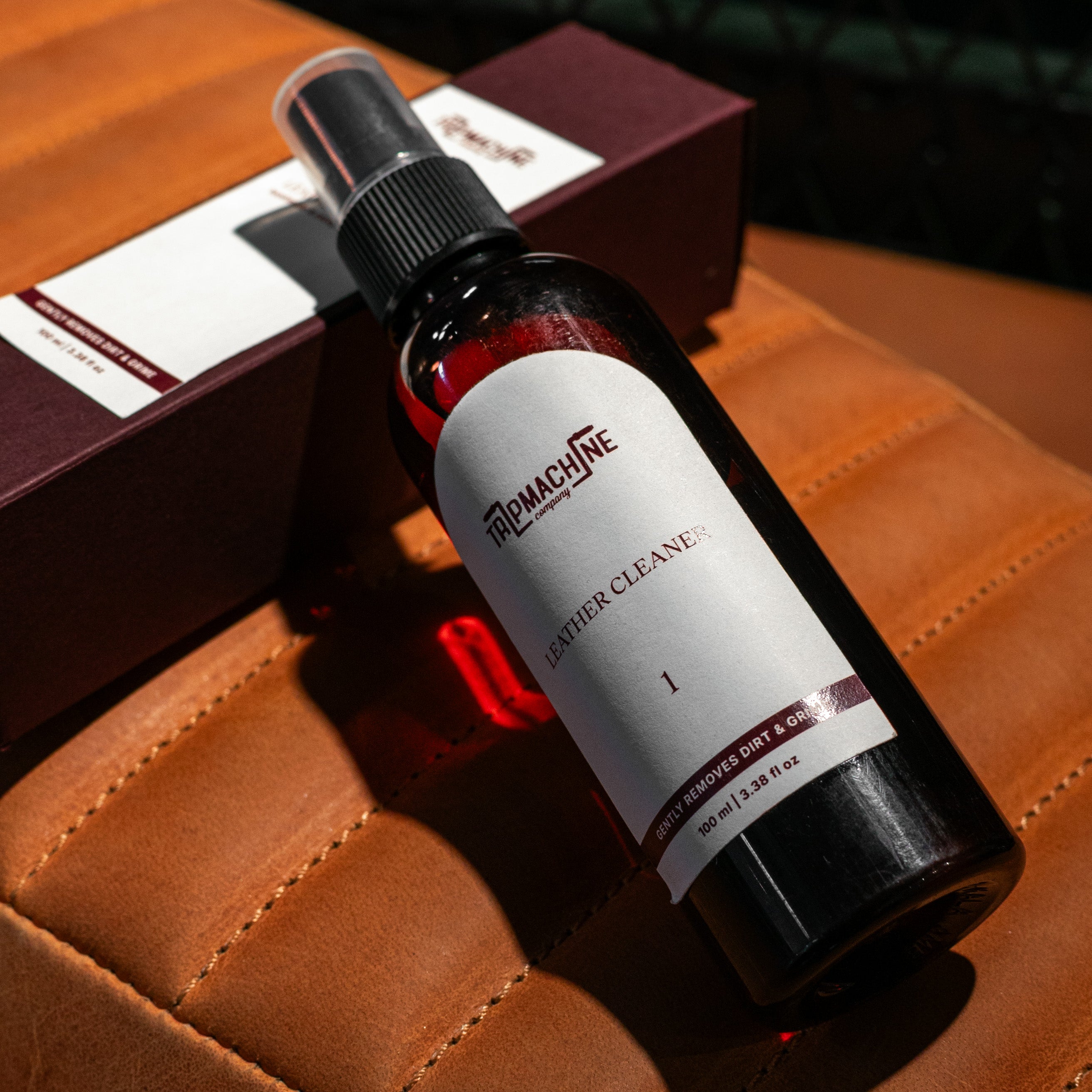 Bottle of Leather Cleaner on a brown leather surface with a box in the background.