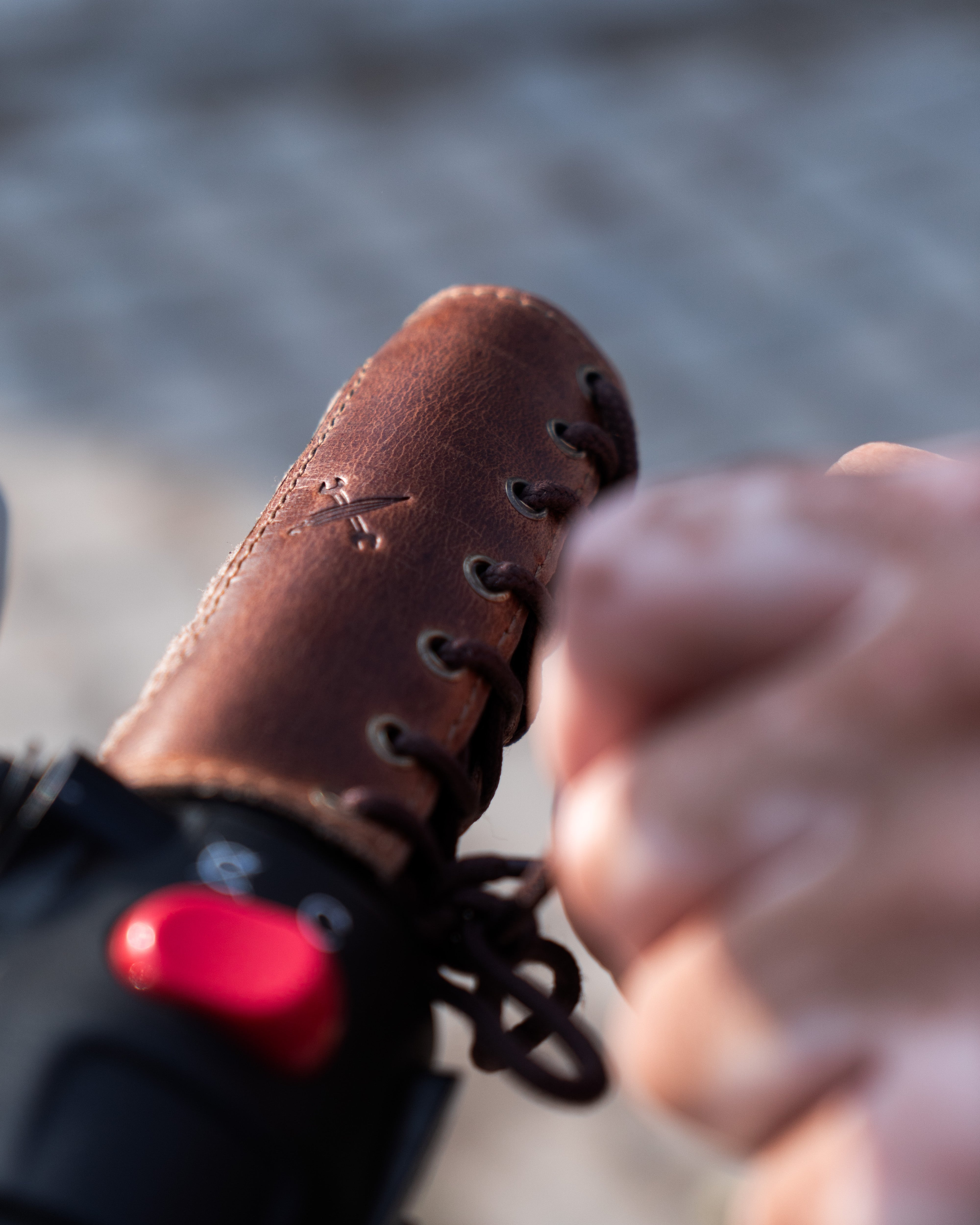 Close-up of a brown leather boot with a red button on a blurred background