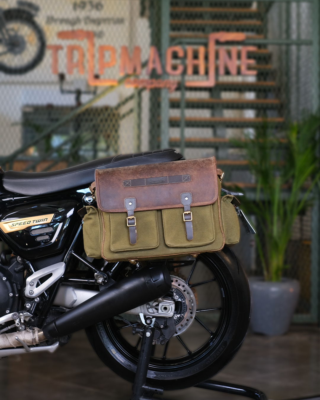 Motorcycle with a brown and green saddlebag in an indoor setting.