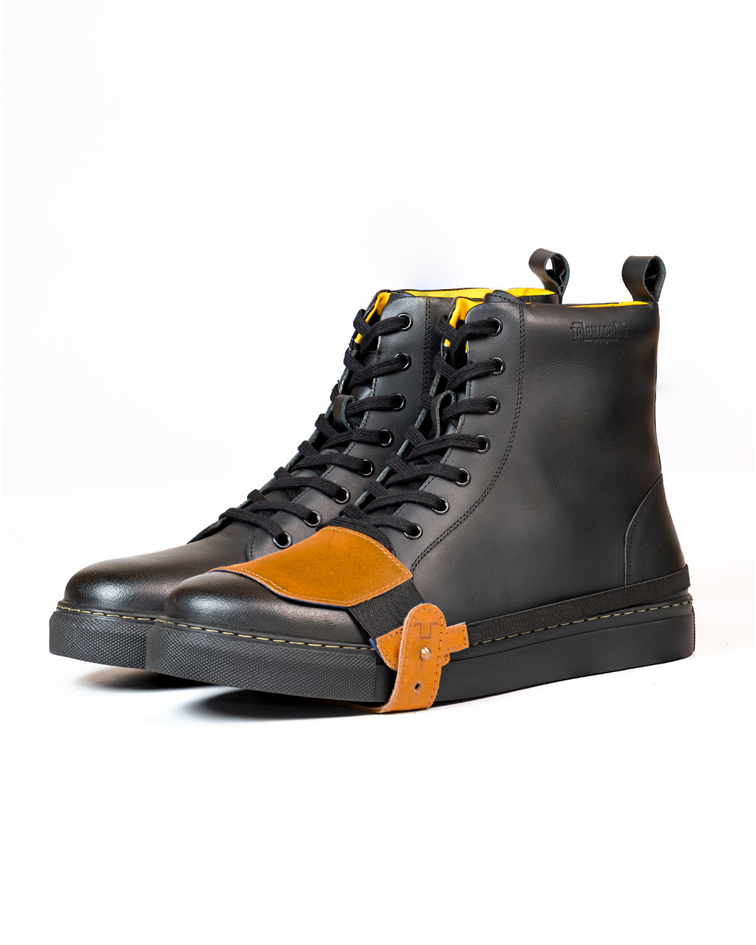 Black sneaker boots with tan shoe protector on a white background