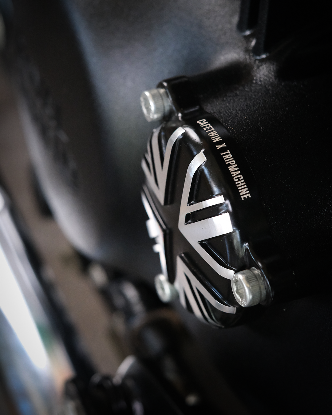 Close-up of a black and silver brake lever with 'Triumph' branding on a dark background.
