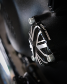 Close-up of a black and silver brake lever with 'Triumph' branding on a dark background.