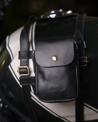 Black leather pouch with gold buckle attached to a motorcycle saddlebag.