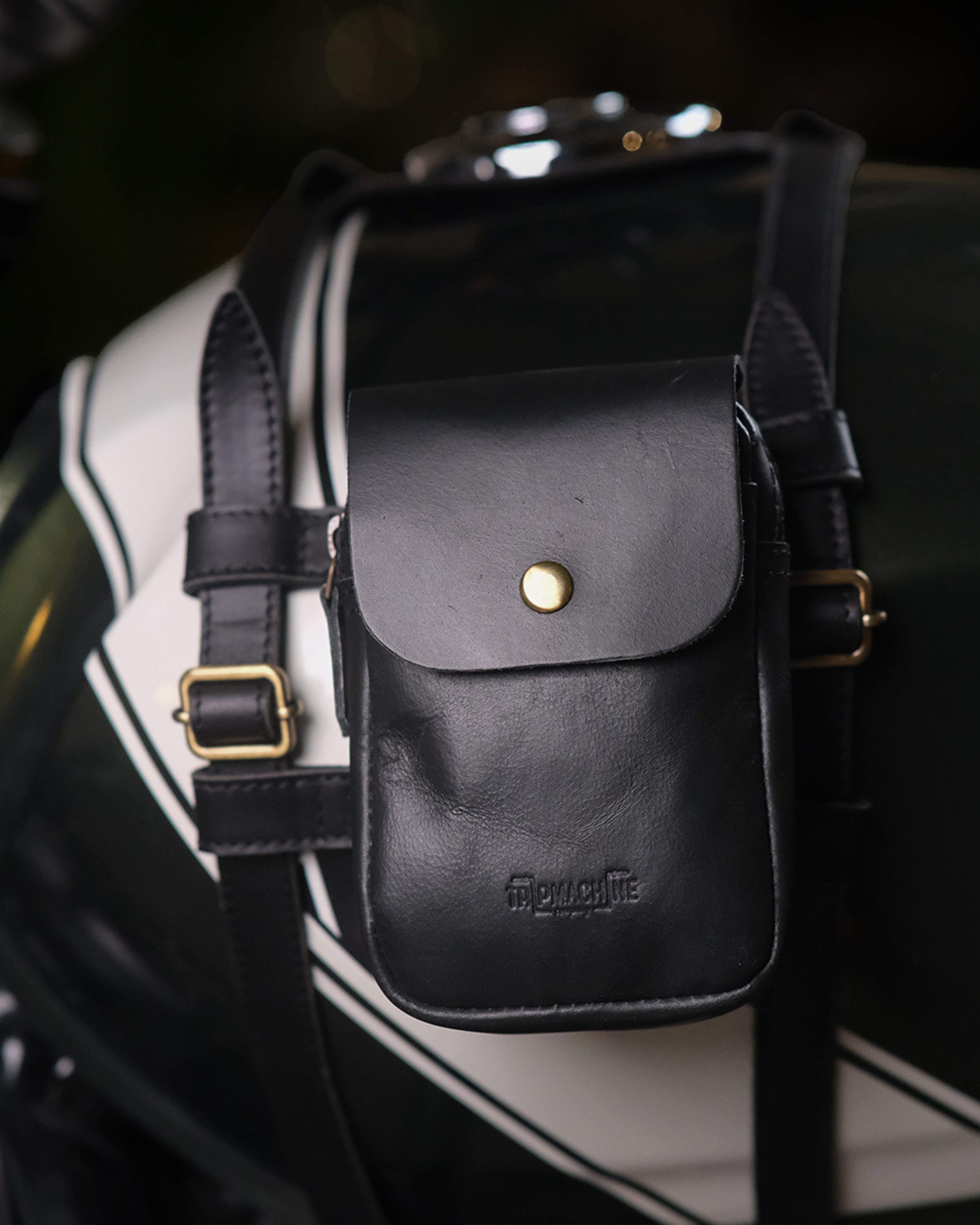 Black leather pouch with gold buckle attached to a motorcycle saddlebag.