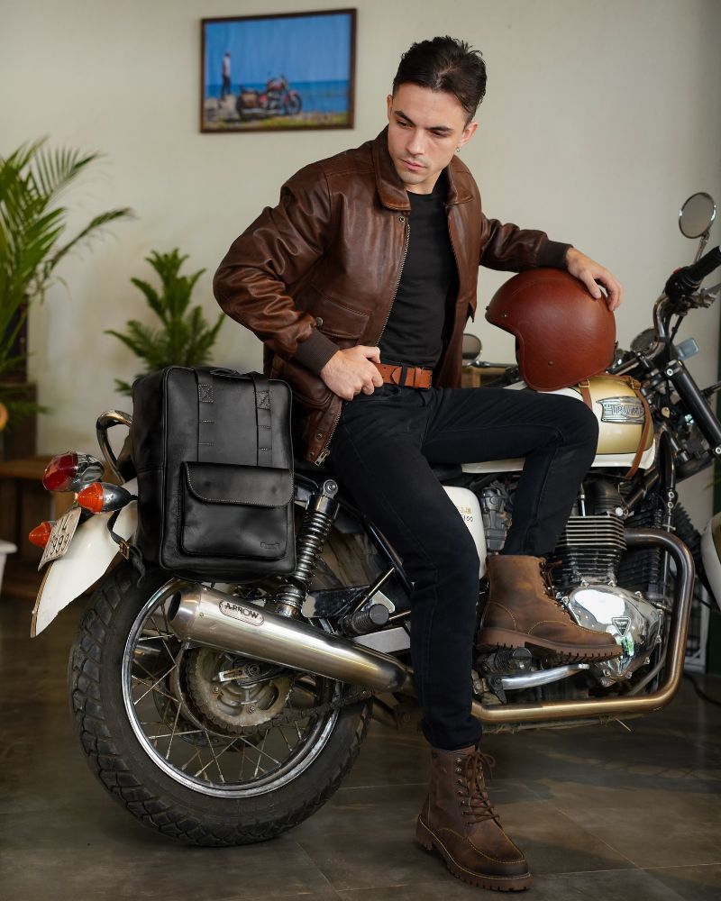 Handmade genuine leather black color eastwood backpack mounted as a saddlebag on a bike and a man seated on motorcycle with moc toe tobacoo boots