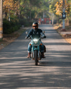 Person riding a motorcycle on a road with trees and a blurred background