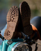 Close-up of brown boots on a motorcycle with a blurred background