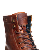 Close-up of a brown leather boot with visible branding on a white background