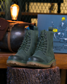 Full view of handmade genuine leather derby forest green boots with ankle, toe and heel protector for bikers on a wooden log