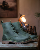 Full side view of handmade genuine leather derby forest green boots with ankle, toe and heel protector for bikers with lamp in the background