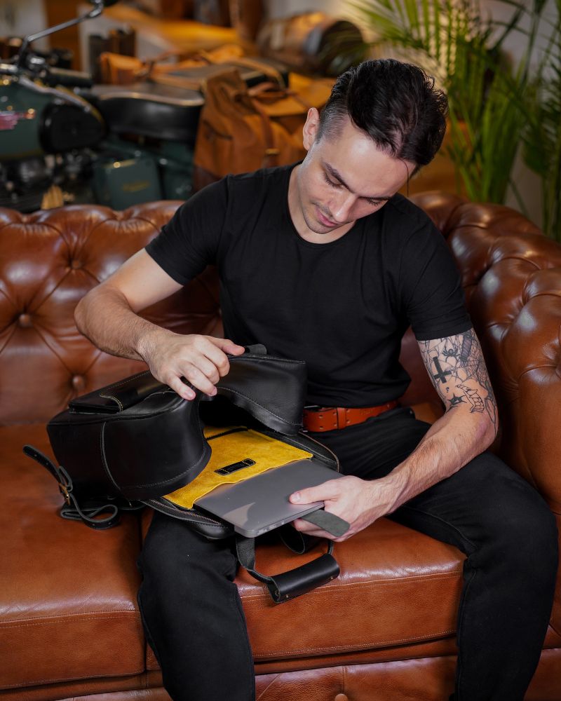 A man putting laptop in detachable sleeve comes with handmade genuine leather black color eastwood backpack