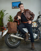 A man seated on a bike with handmade genuine leather brown color eastwood backpack mounted on a bike as saddlebag