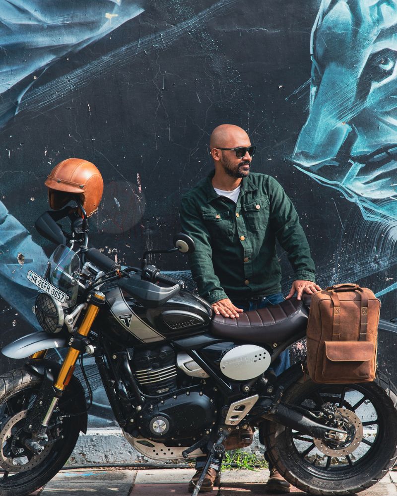 A man standing with handmade genuine leather brown color eastwood backpack mounted on a bike as saddlebag