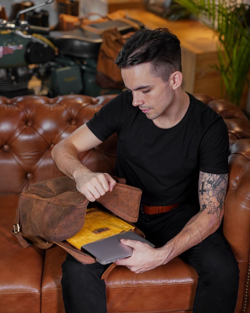 A man putting laptop in a detachable sleeve comes with handmade genuine leather brown color eastwood backpack