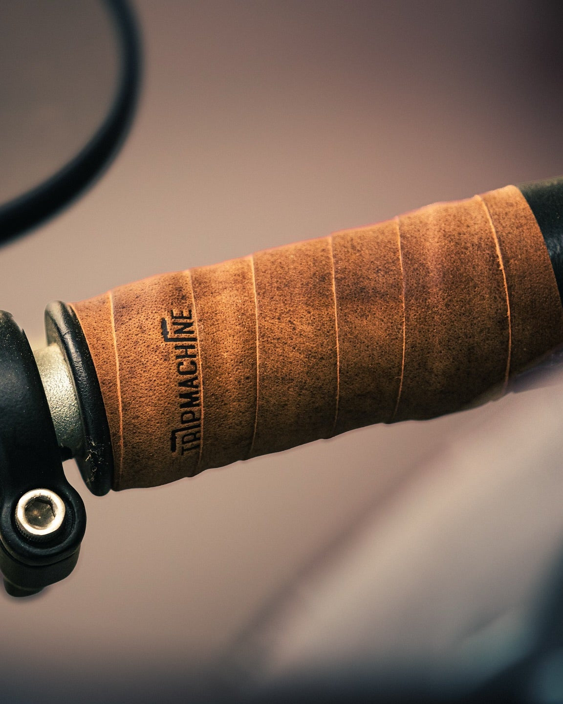 Close-up of a brown handlebar grip with 'Tripmachine' branding on a blurred background