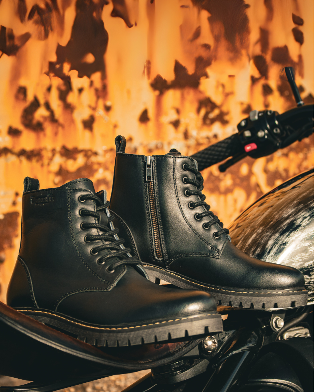 Black leather boots on a motorcycle with a fiery background