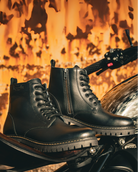 Black leather boots on a motorcycle with a fiery background