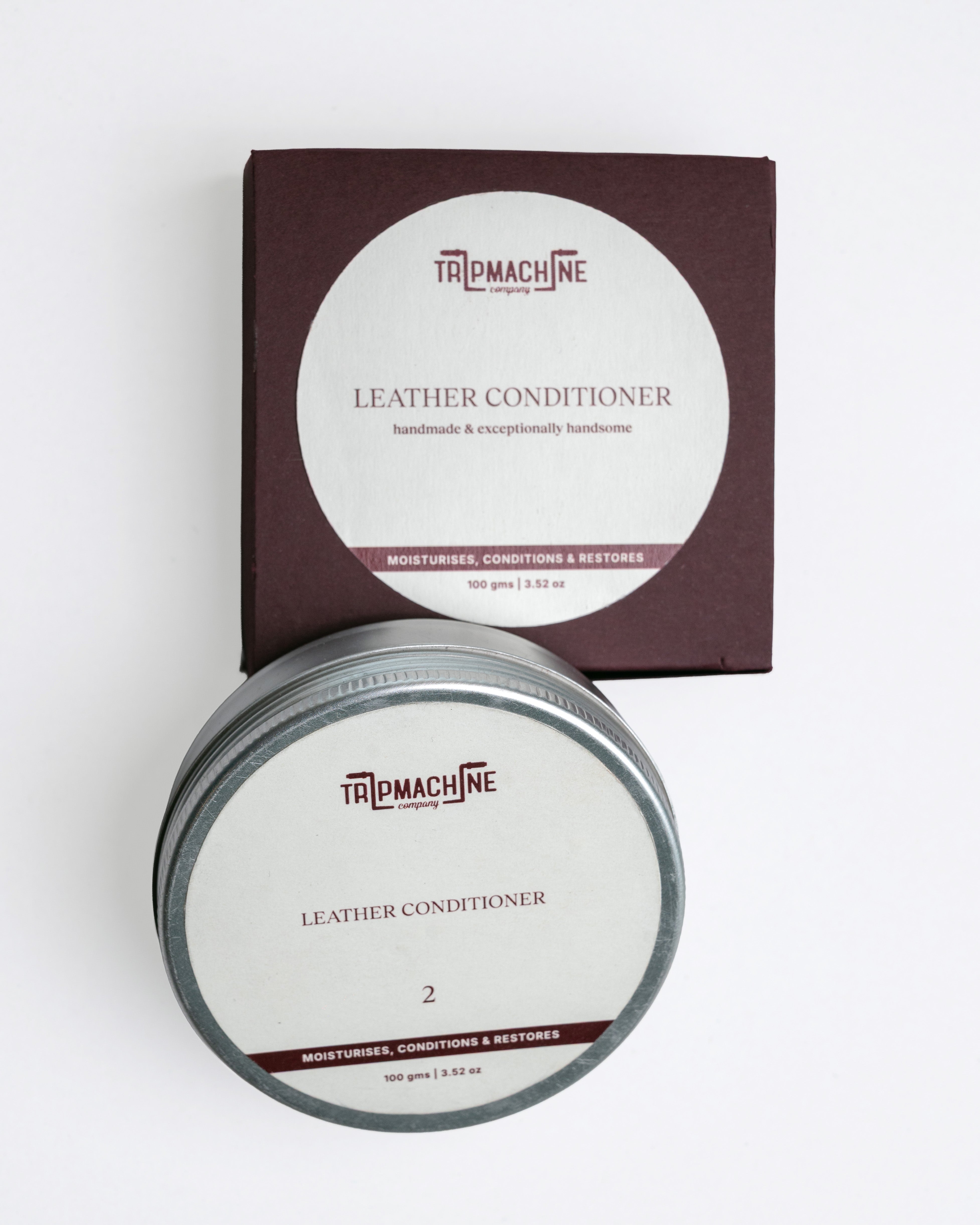 Tin of leather conditioner with packaging on a white background