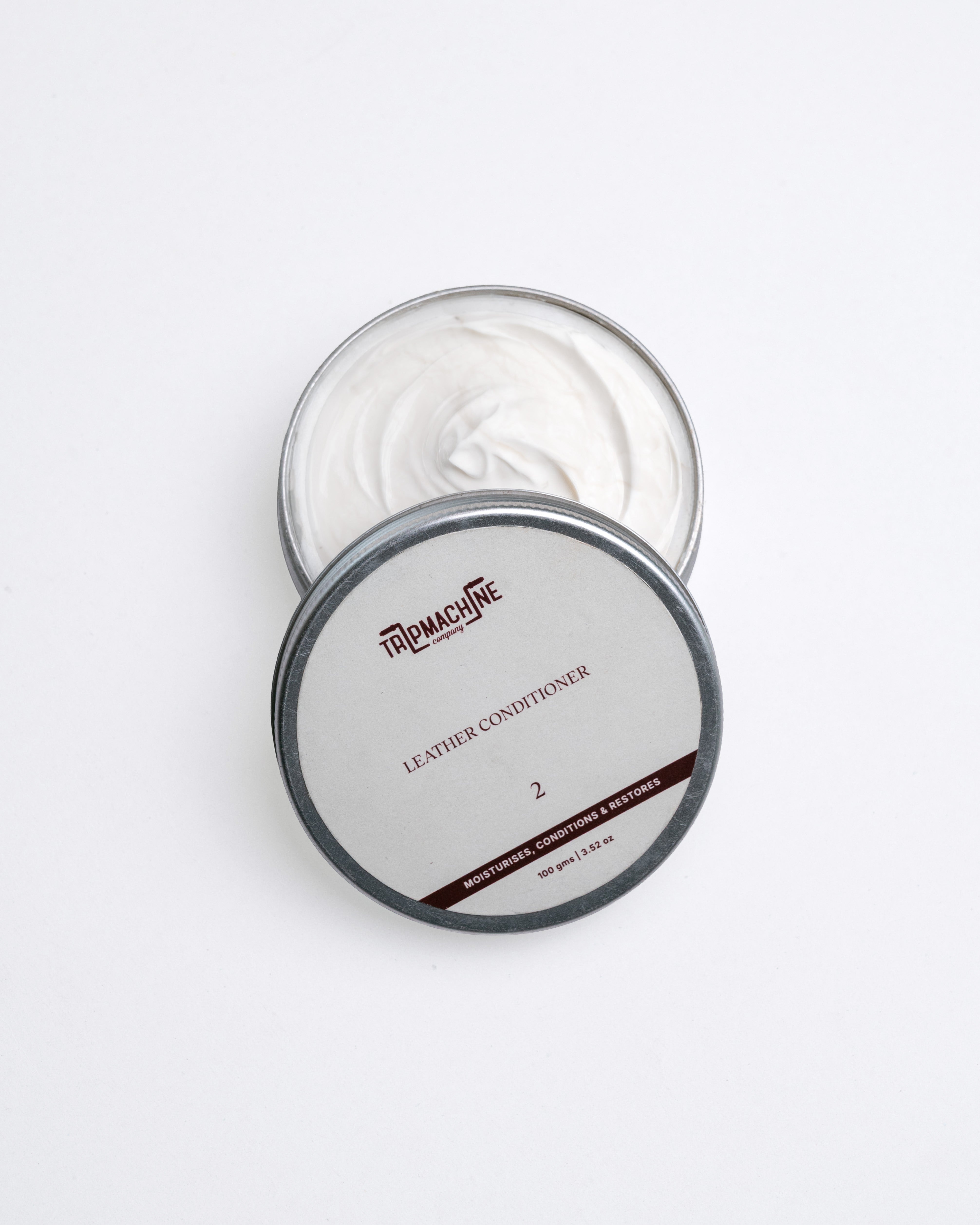 Open container of leather conditioner with visible brand name on a white background