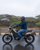 Person riding a motorcycle on a wet road with trees in the background
