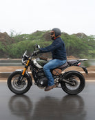 Man riding a motorcycle on a road with trees in the background