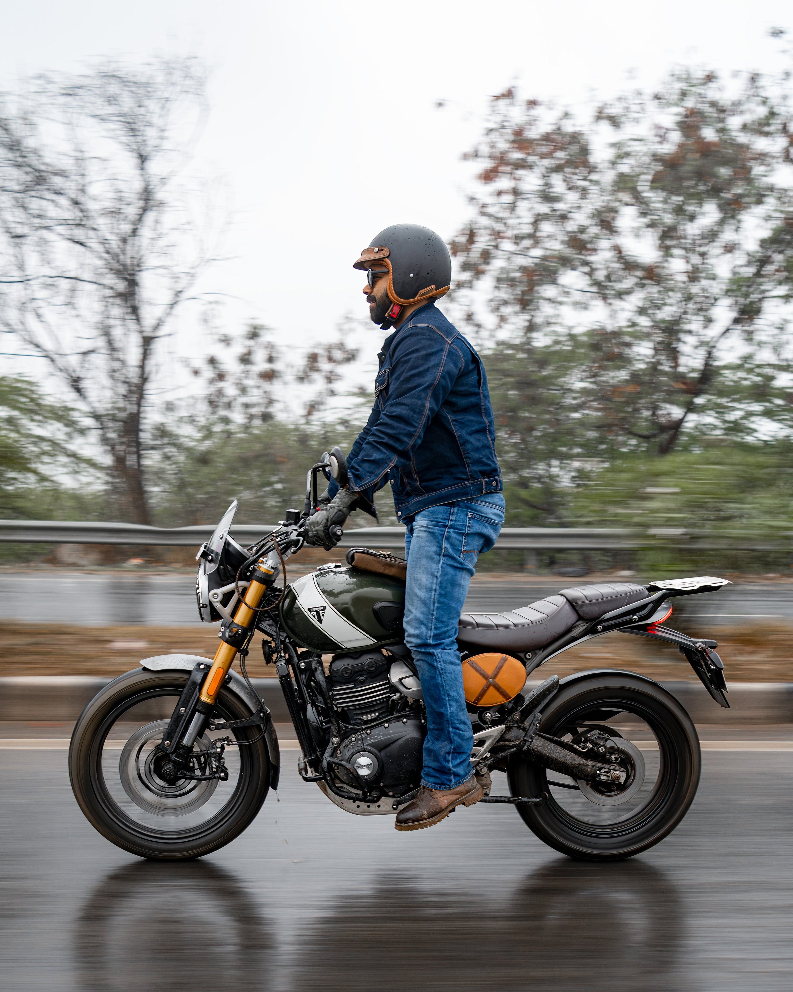 Person on a motorcycle on a wet road with trees in the background
