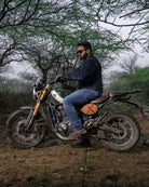 Man sitting on a motorcycle in a forested area