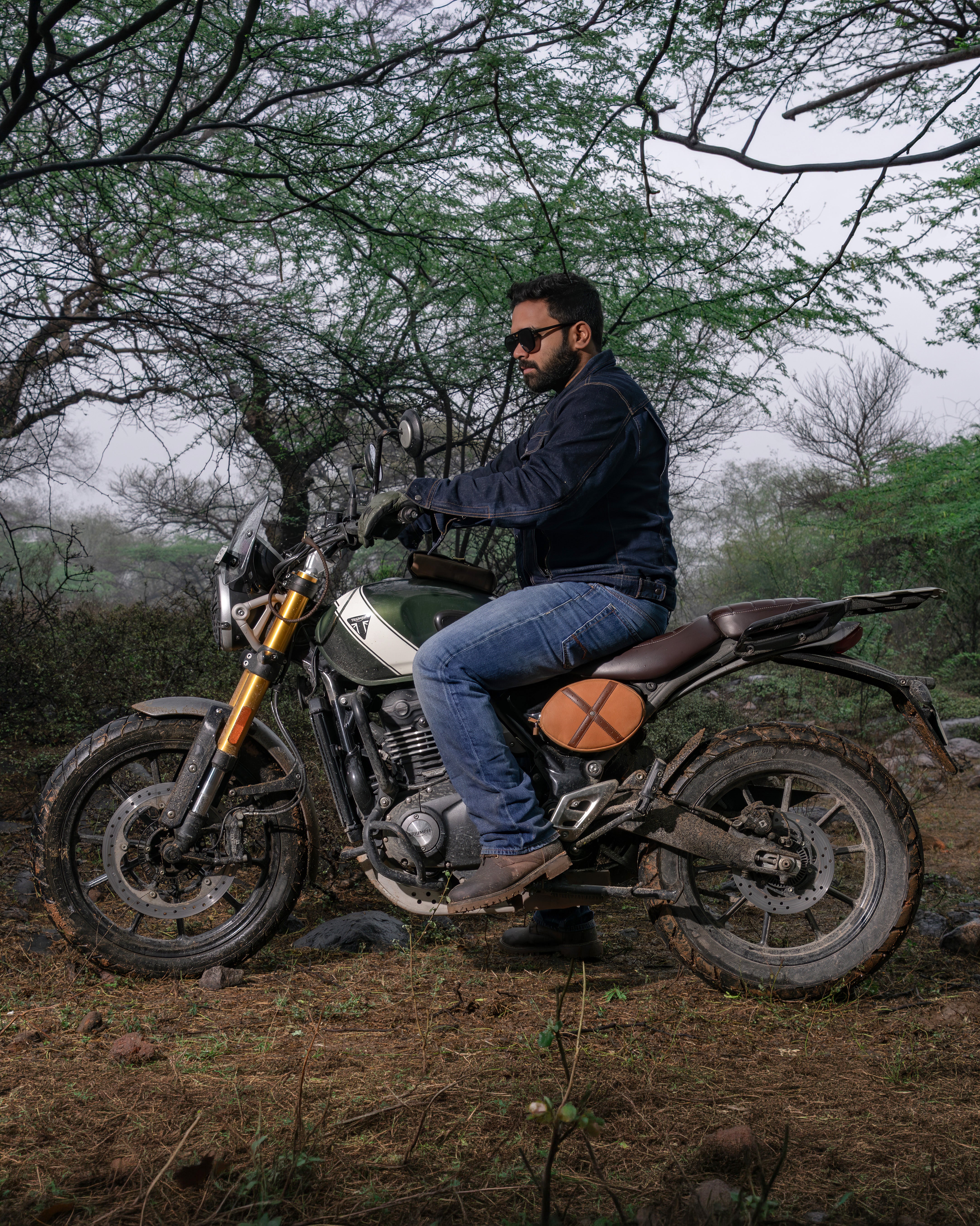 Man sitting on a motorcycle in a forested area
