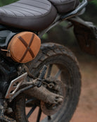 Close-up of a motorcycle with a brown leather bag on a blurred natural background