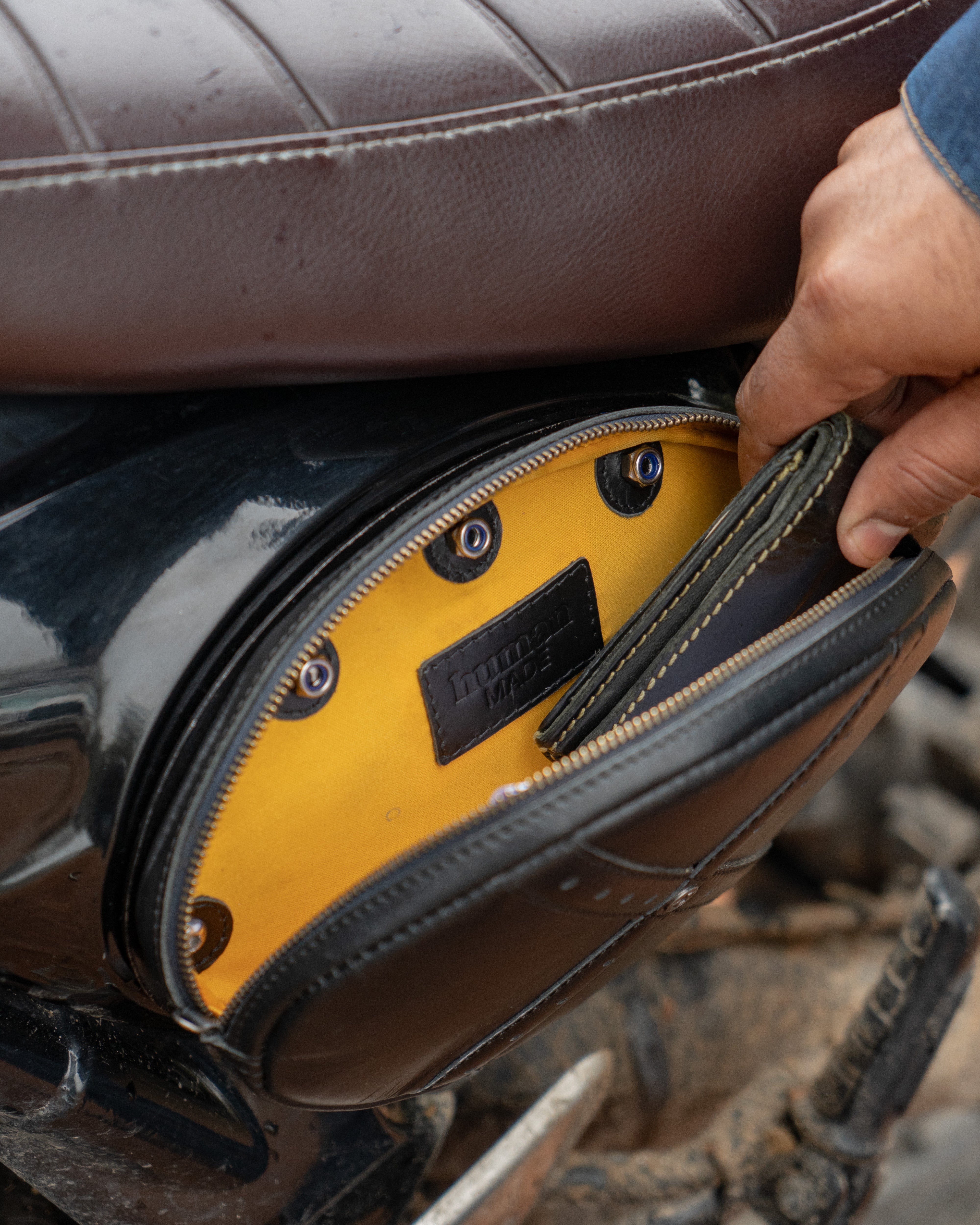 Close-up of a person opening a motorcycle saddlebag with a yellow interior.
