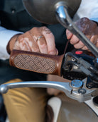 Close-up of hands gripping motorcycle handlebars with leather grips