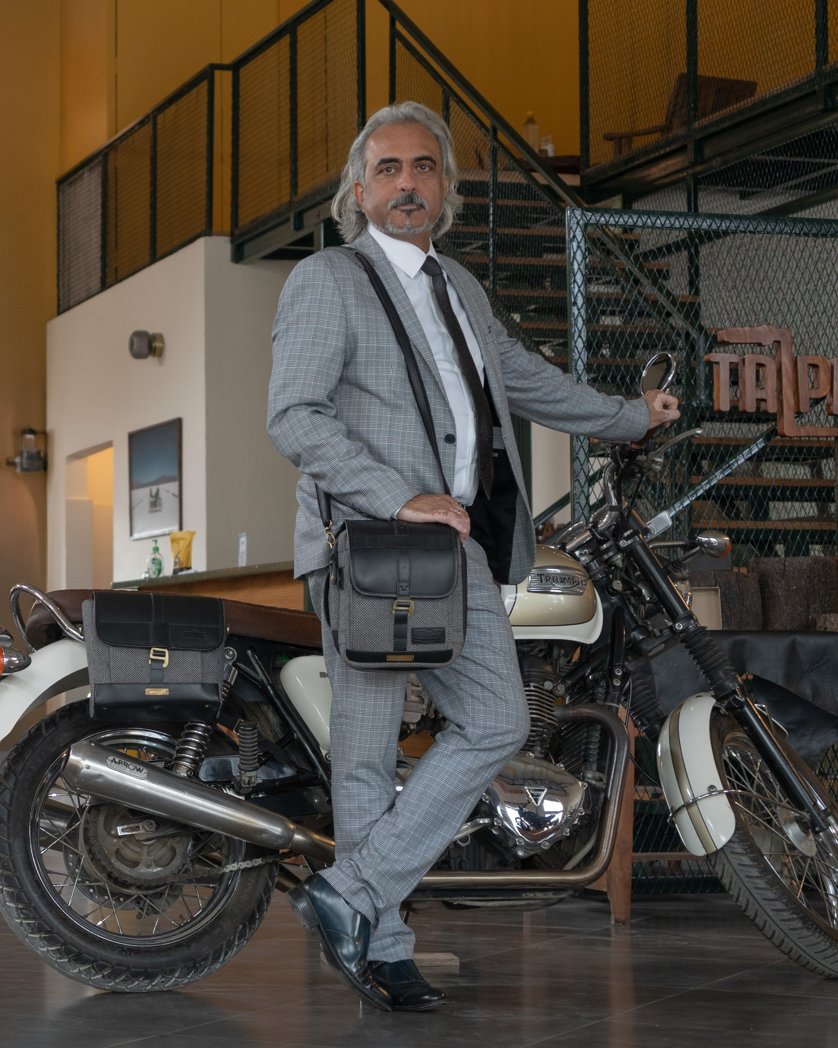 Man in a suit standing next to a motorcycle in an indoor setting